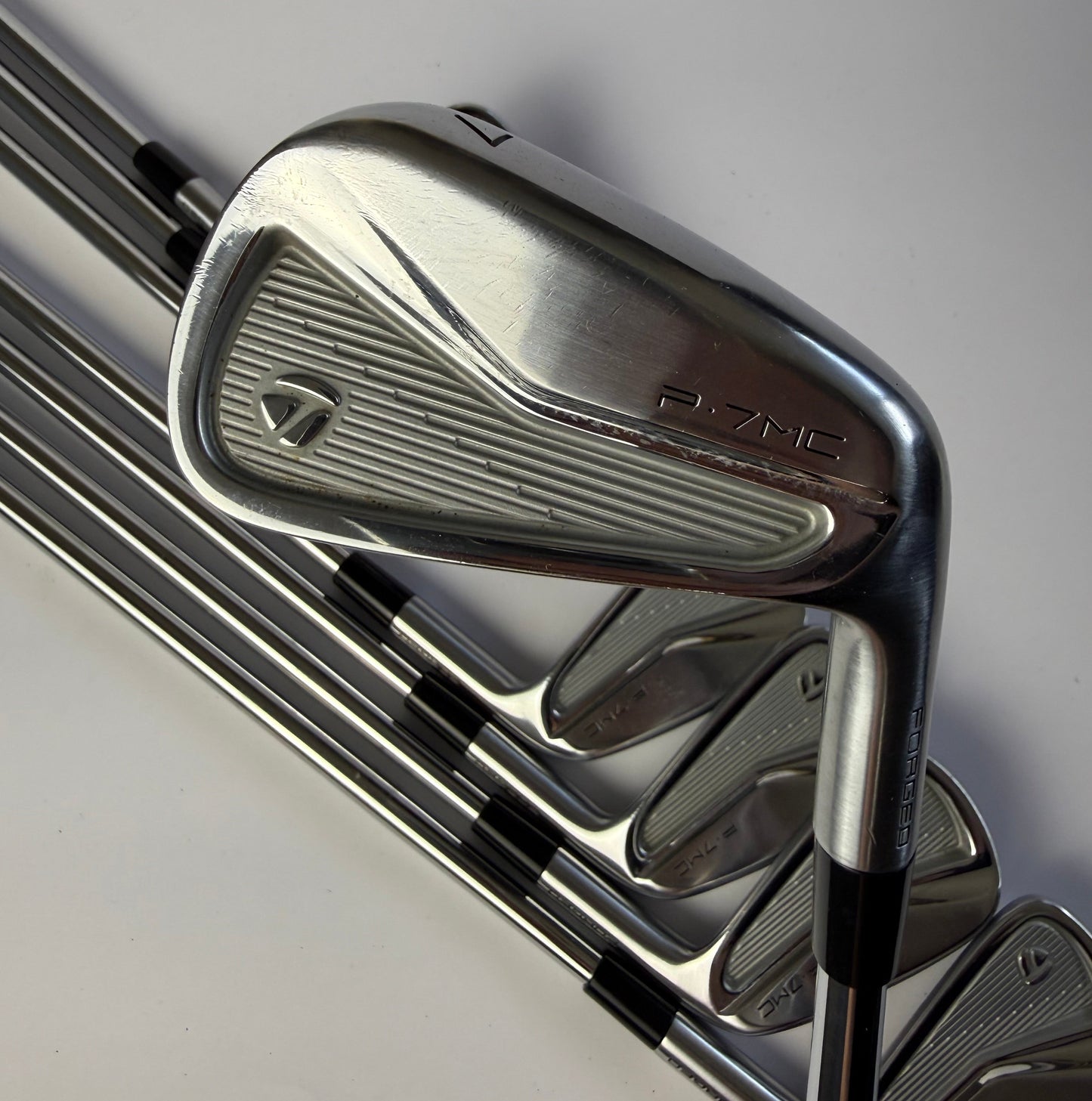 Taylormade P7MC iron golf clubs on a light gray background